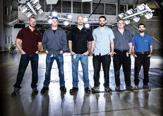 WCC graduates (from left) John Smith, Derek Gaylord, Ross Edgar, Doug Nelson, Tim Shriner and David Vella gather in the crash hall at the Toyota Technical Center’s safety test facility. (Brian Watkins/Toyota)