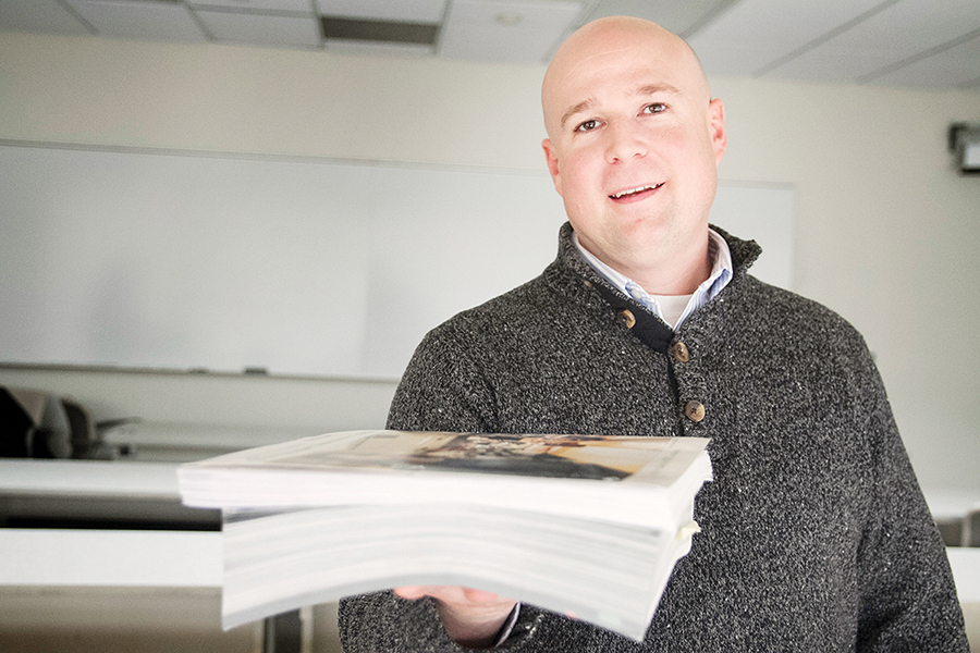 WCC Business instructor Doug Waters holding an expensive textbook that he replaced with a free online alternative